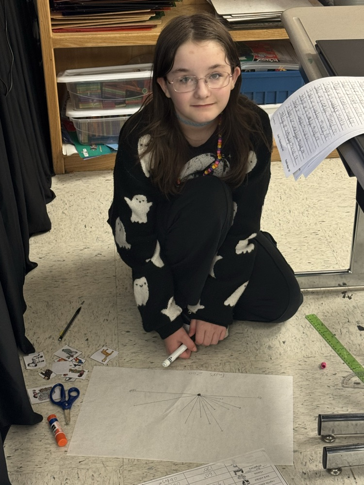 A student sits in the floor working on the class’s zoo-themed angle project