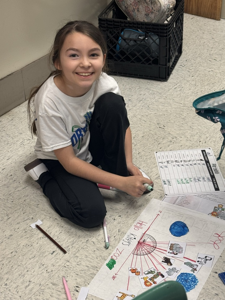 A student sits in the floor working on the class’s zoo-themed angle project.