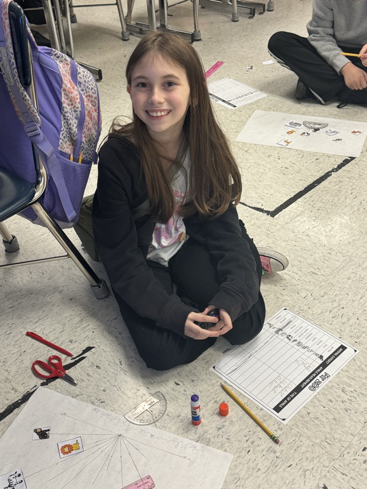 A student sits in the floor working on the class’s zoo-themed angle project.