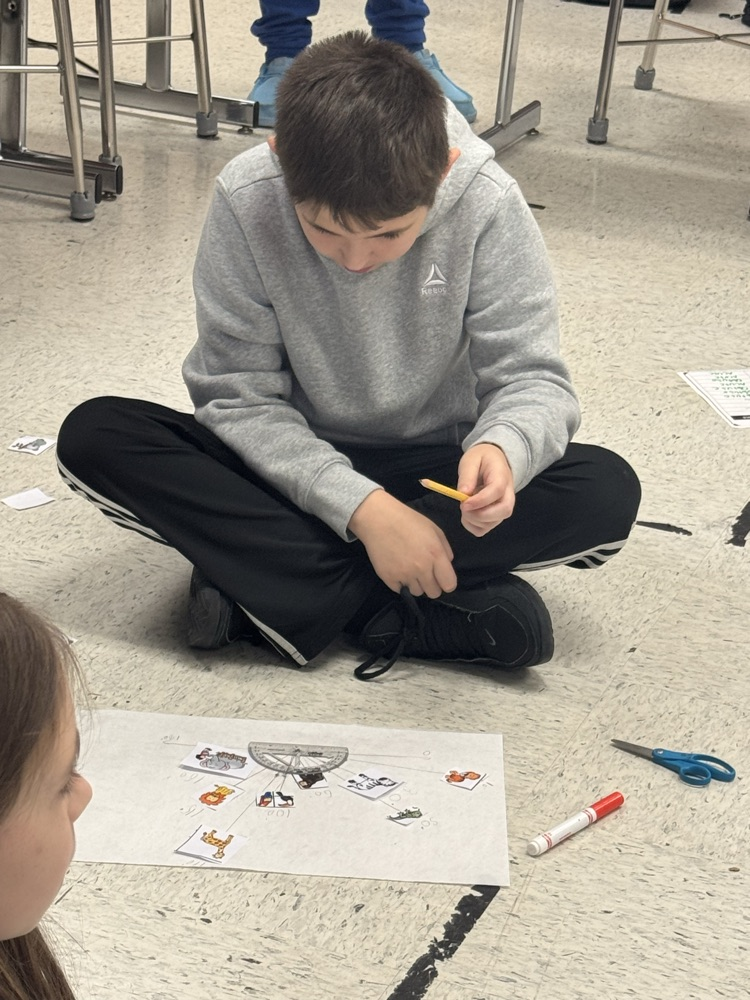A student sits in the floor working on the class’s zoo-themed angle project.