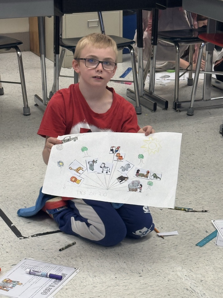 A student sits in the floor working on the class’s zoo-themed angle project.