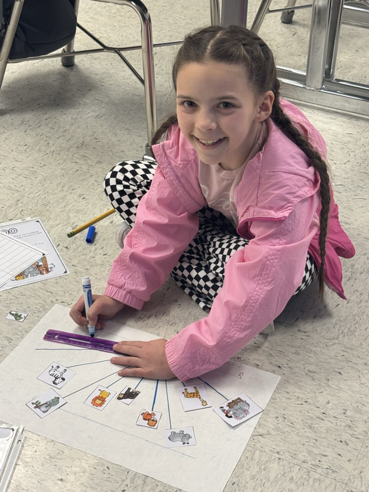A student sits in the floor working on the class’s zoo-themed angle project.