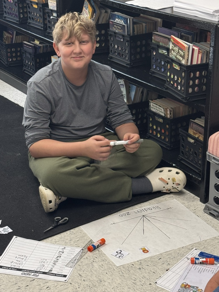 A student sits in the floor working on the class’s zoo-themed angle project.