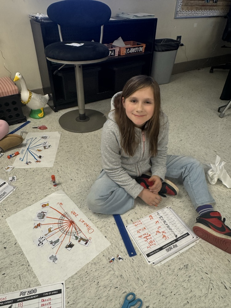 A student sits in the floor working on the class’s zoo-themed angle project.