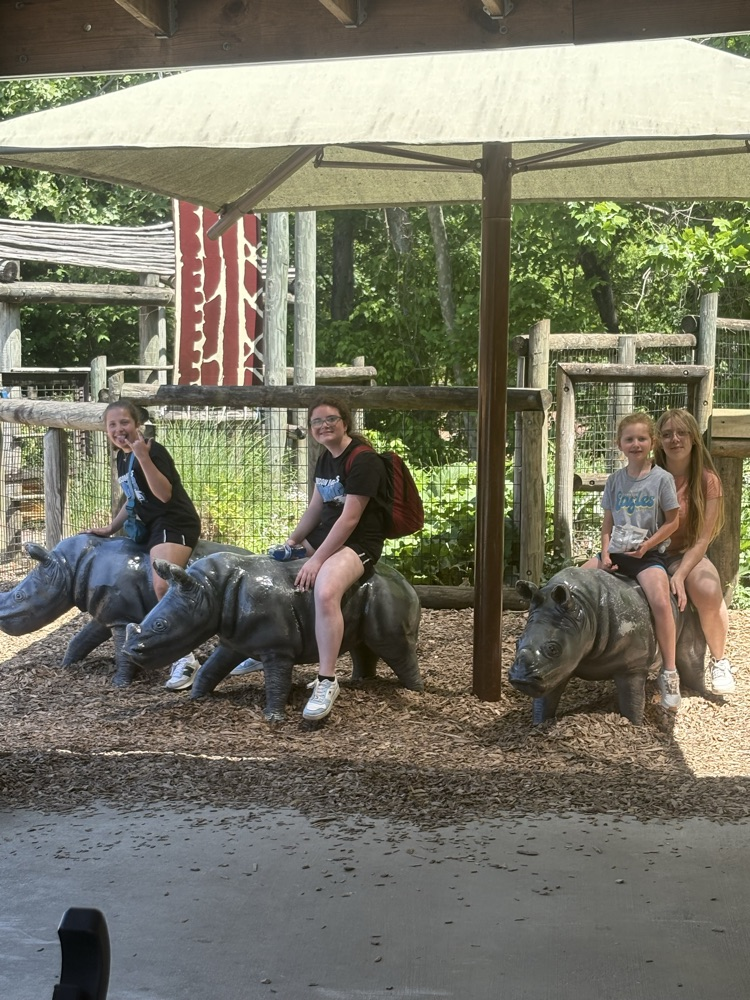 Three children sit atop three different bronze rhino statues at Zoo Knoxville  
