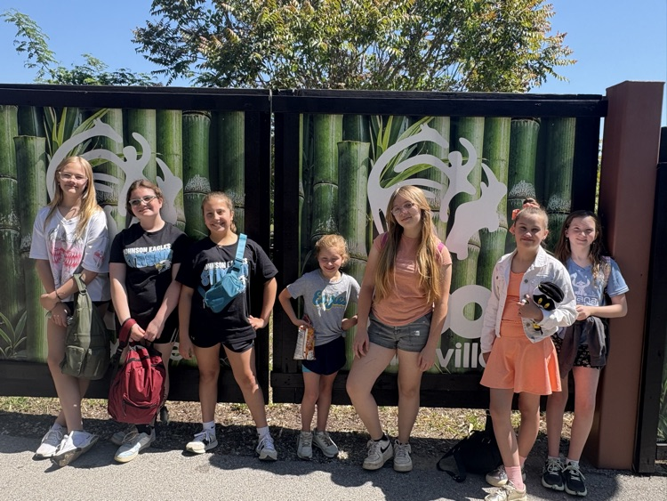 A group of seven students smile for a picture in front of a Zoo Knoxville sign  