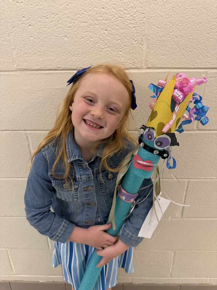 A girl in a denim jacket holds her teal pool noodle stick horse with bright colored mane  