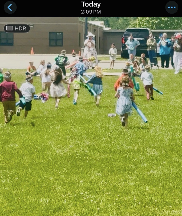 A group of students holding pull doodle, stick horses race across a field.