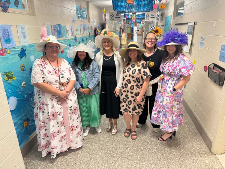 A group of six school staff stand together for a picture dressed in their derby day attire with hats.