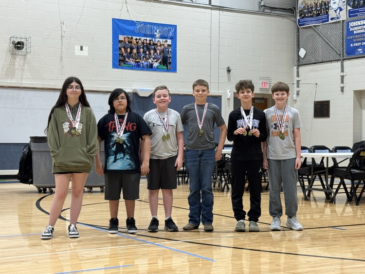Students stand in line in the Johnson Elementary gym with certificates and medals celebrating their 2025 KSA test scores. 