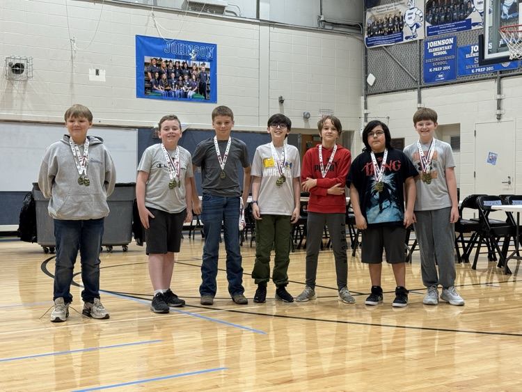 Students stand in line in the Johnson Elementary gym with certificates and medals celebrating their 2025 KSA test scores. 