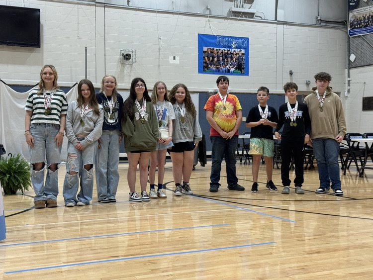Students stand in line in the Johnson Elementary gym with certificates and medals celebrating their 2025 KSA test scores. 