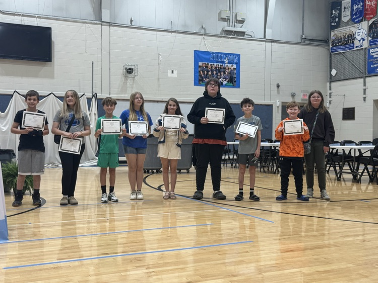 Students stand in line in the Johnson Elementary gym with certificates and medals celebrating their 2025 KSA test scores. 