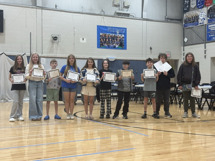 Students stand in line in the Johnson Elementary gym with certificates and medals celebrating their 2025 KSA test scores. 