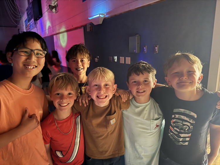 A group of boys stand close together, smiling for a picture in the school gym  