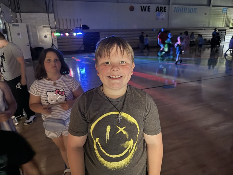 A boy smiles while standing in the school gym, which is darkened for the school dance  