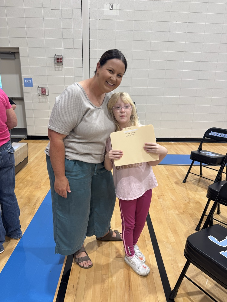 A teacher and her student smile for the camera after the girl receives her awards.