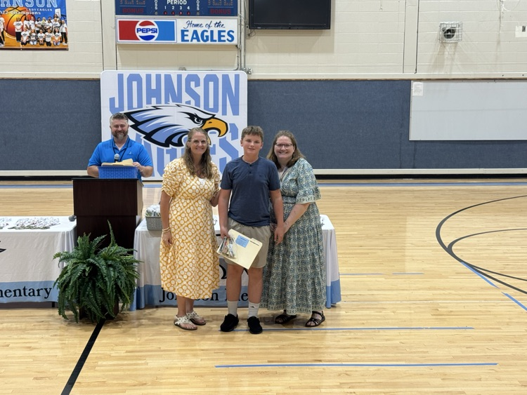 Mrs. Bullard, left, and Mrs. Sprinkle, right, stand with a male student as he receives his awards in the gym. Mr. Hensley, principal, is to the left and just behind them, where he has been hanging out awards