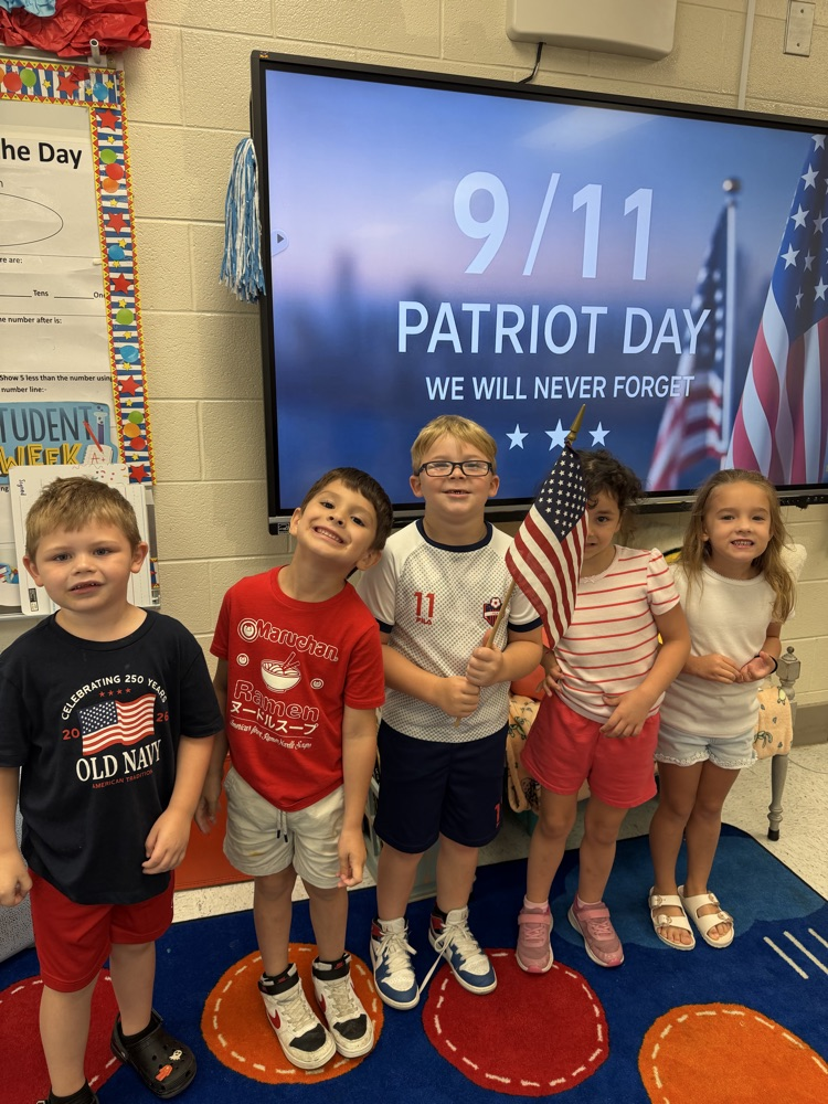 A line of five children stand in front of a ViewSonic board displaying patriotic imagery. the middle child holds an American flag  