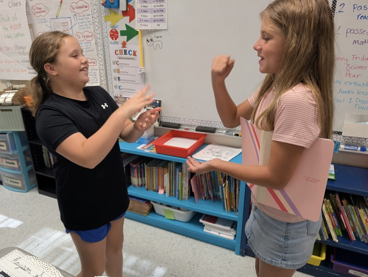 two girls play rock paper scissors, while deciding who will go first in their collaborative activity.