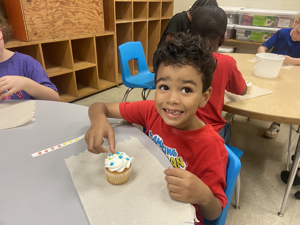 A little boy looking at his cupcake.