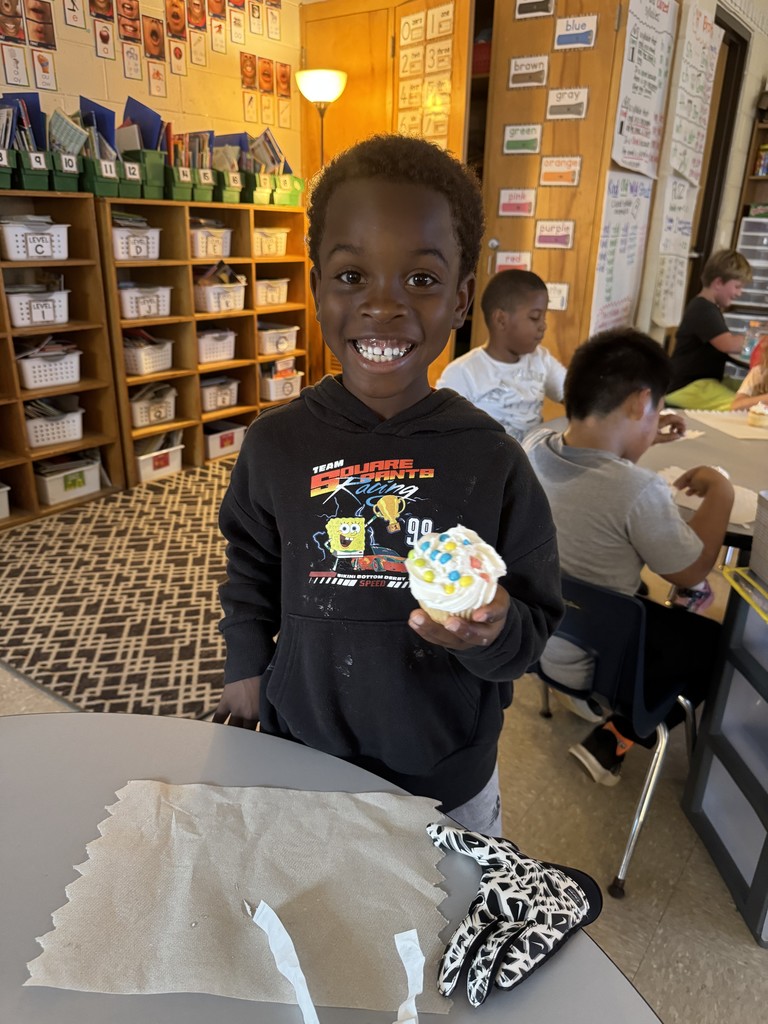 A boy holding a cupcake and smiling