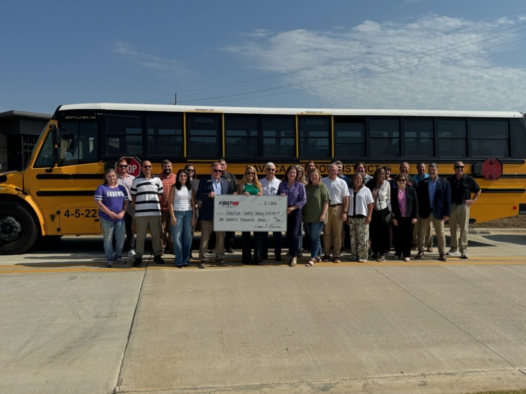 Local School District representatives standing in front of a school bus, to honor the donation of FNB to the New Library