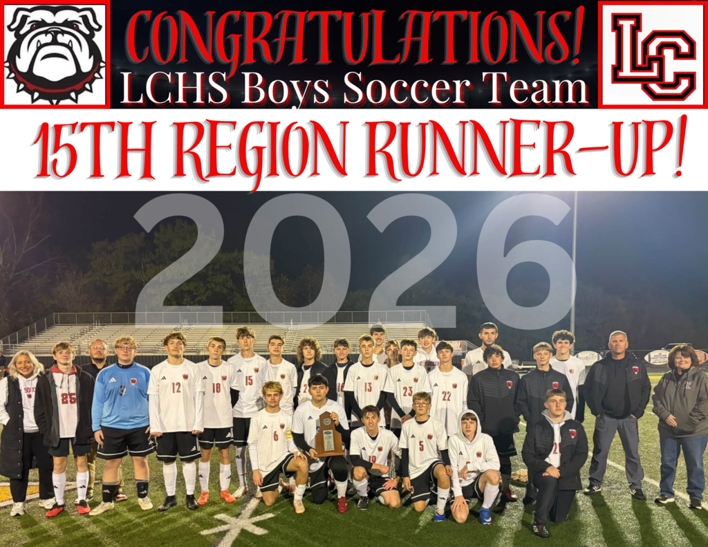 A soccer team in white uniforms stands on a field, with adults in jackets behind them, a trophy on the ground.
