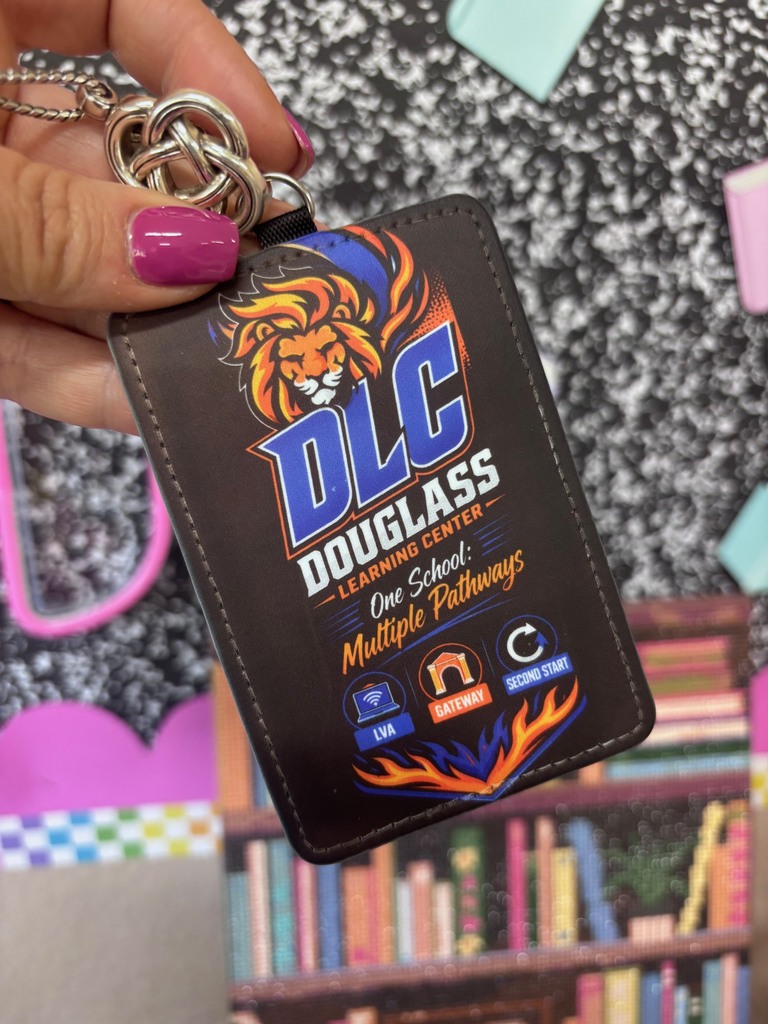 Hand holds black ID card featuring lion logo, text "DLC DOUGLASS Learning Center, One School, Multiple Pathways." Background shows bookshelf with books.