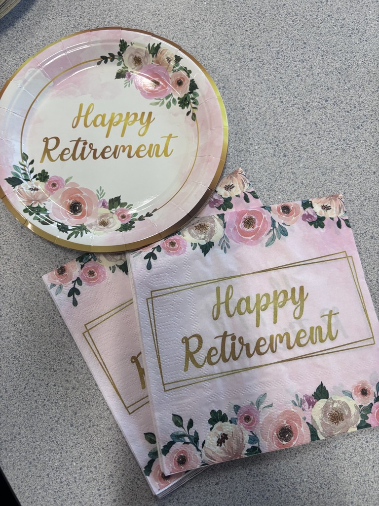 A pink plate and two napkins with "Happy Retirement" text and floral patterns on a gray surface.