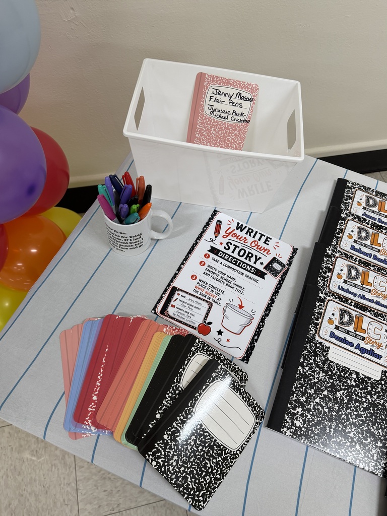 Table displays notebooks, pencils, a cup, cards, and a box with balloons in the background.