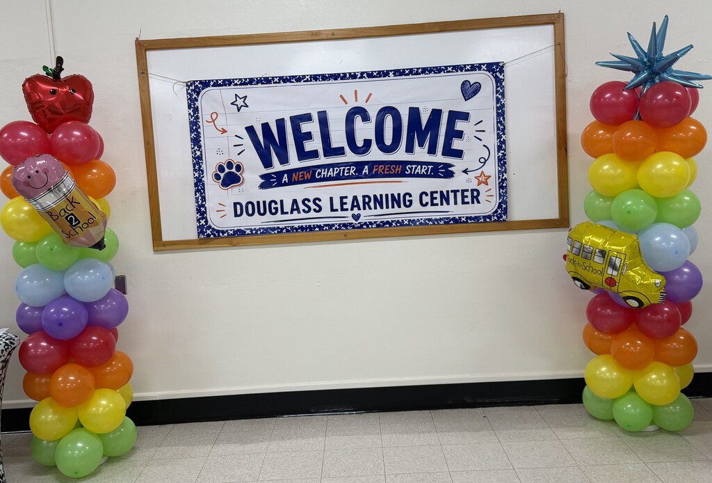 Two balloon columns, one with a strawberry and pencil, the other with a pineapple. A banner reads "Welcome."