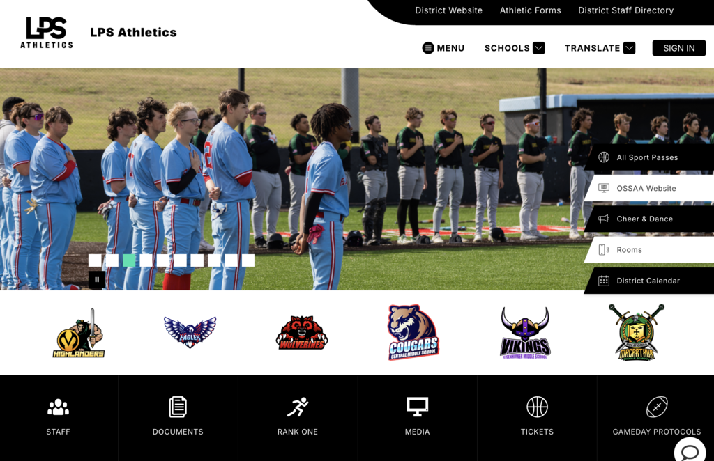 A sports team stands on a field with a grassy background. They are wearing blue uniforms. Logos appear below.