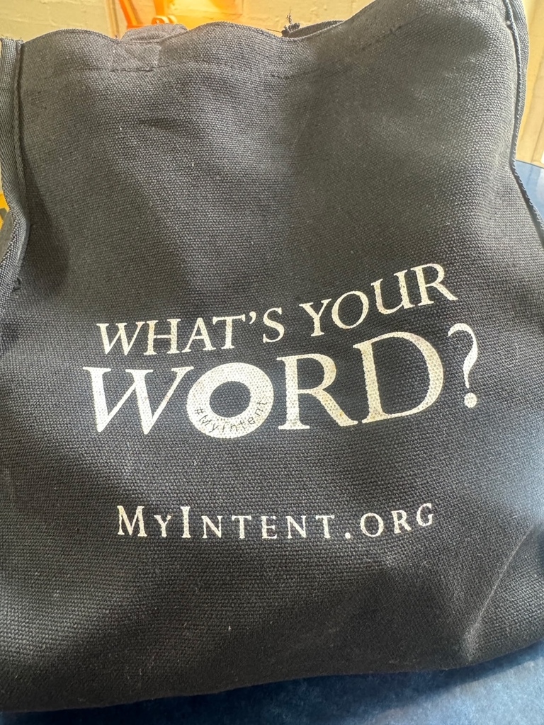 A black canvas tote bag features the words "What's Your Word?" and "MyIntent.org" in white text.