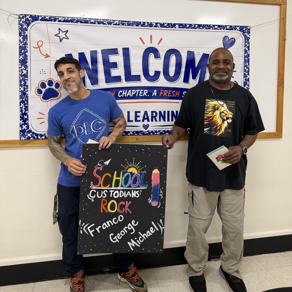 Two men pose with a blackboard displaying "School Rocks" and a banner reading "Welcome Chapter A Fresh Learning."