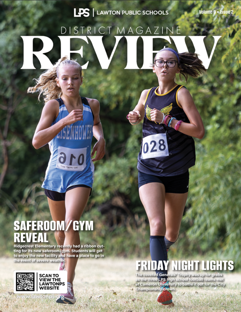 Cover of a magazine featuring two female runners in a race. They wear numbered bibs. Text reads "Review", "Saferoom/Gym Reveal", and "Friday Night Lights".