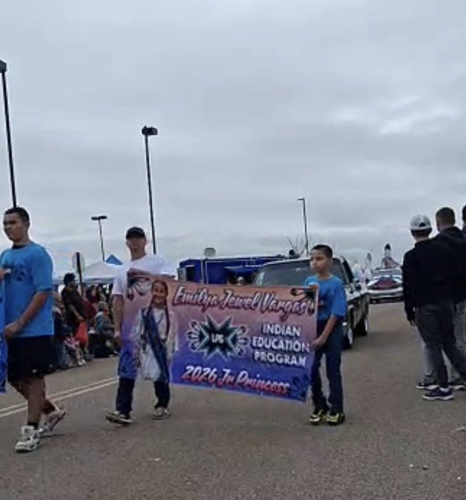 A group of people in an outdoor area. Some hold a banner with text promoting the 2026 Indian Education Program.