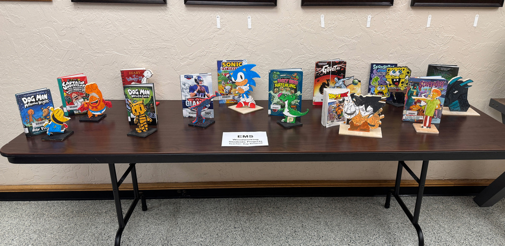 Display of various character figurines on a table with a sign in the center.