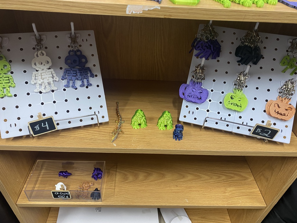 Display board with pegs holding colorful Halloween charms. One board has a label reading '4'.