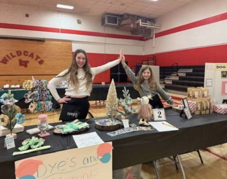 Picture of two girls high-fiving each other at a marketplace table
