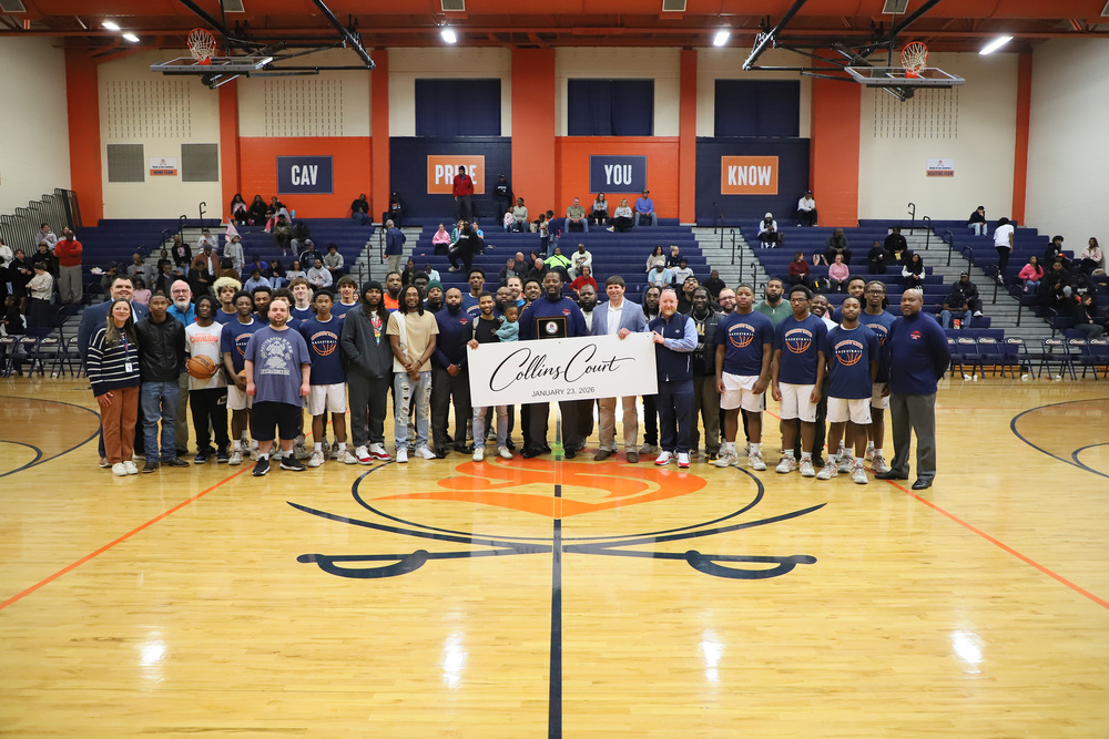 Southern Lee Men’s Basketball Coach Gaston Collins is surrounded by former players, his current team, and long-time colleagues as the school announced that it was naming the basketball court in the school’s main gymnasium in his honor during a surprise pre-game ceremony before the Cavaliers’ game against Harnett Central on February 10, 2026.