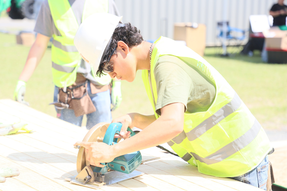 Student cuts a wood panel with power saw