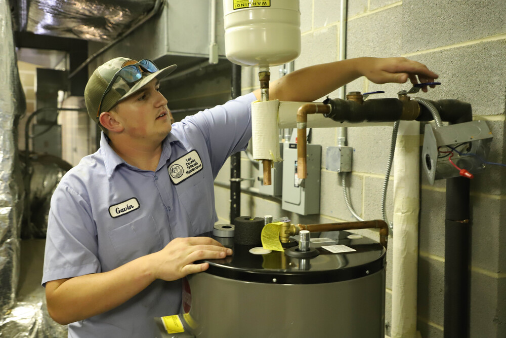 Maintenance Worker installing hot water heater in a cinder block room