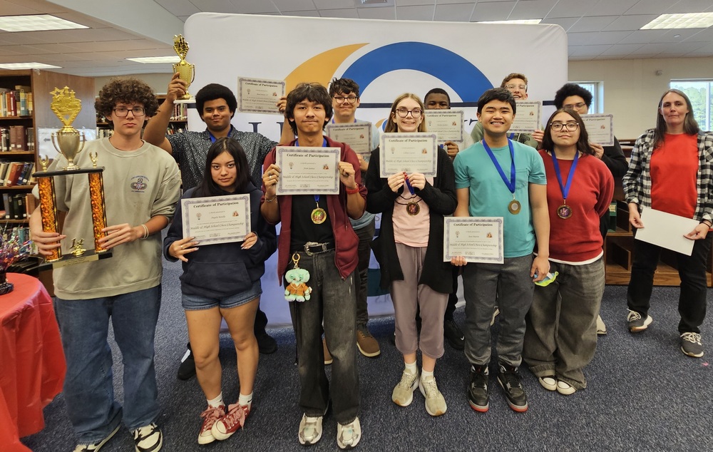 Lee Early College’s chess team poses with their recognition certificates and trophies following earning a third consecutive LCS Secondary District Chess Championship. The Cobras team is coached by Shannon Willaert and secured 19 of a possible 24 match points during the 2026 edition of the tournament.