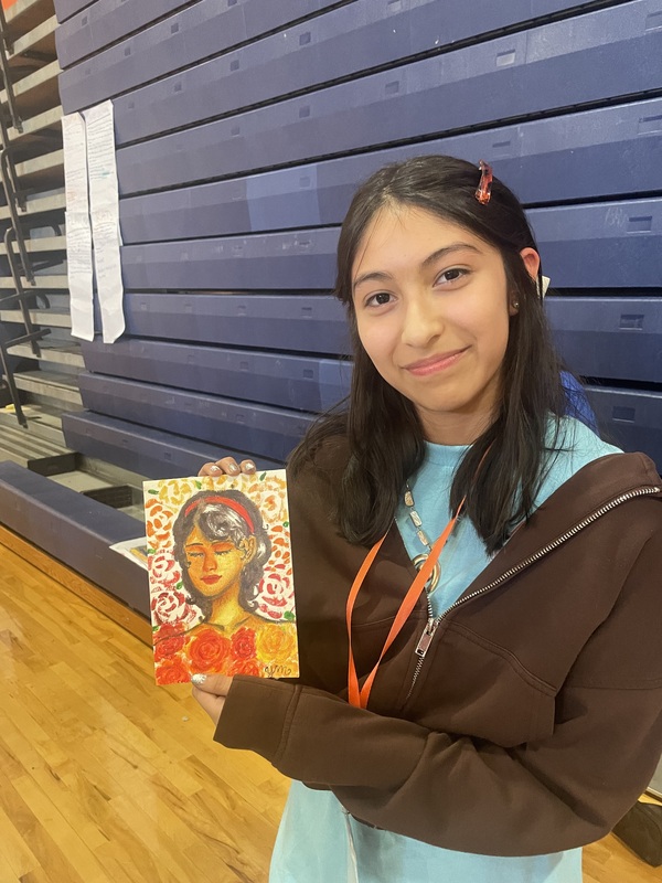 Yasmin M holds up a self portrait she made during visual arts at Kaleidoscope 2026