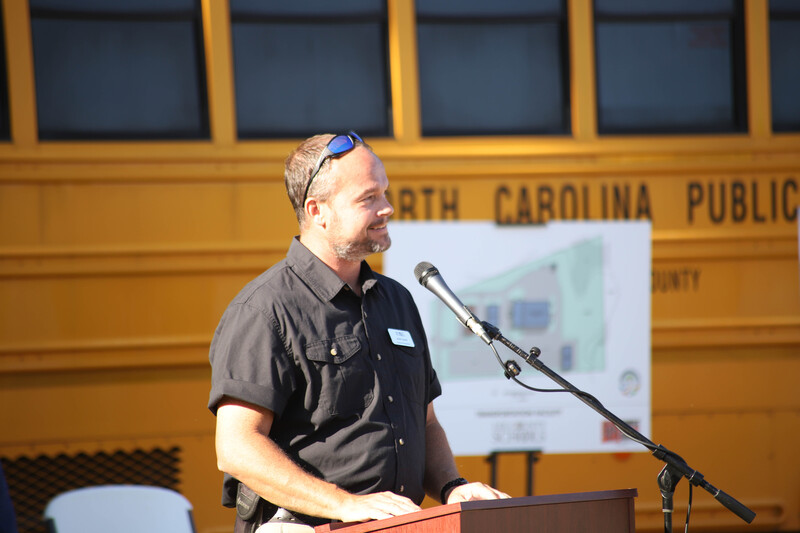Justin Covert speaks to groundbreaking infront of a bus