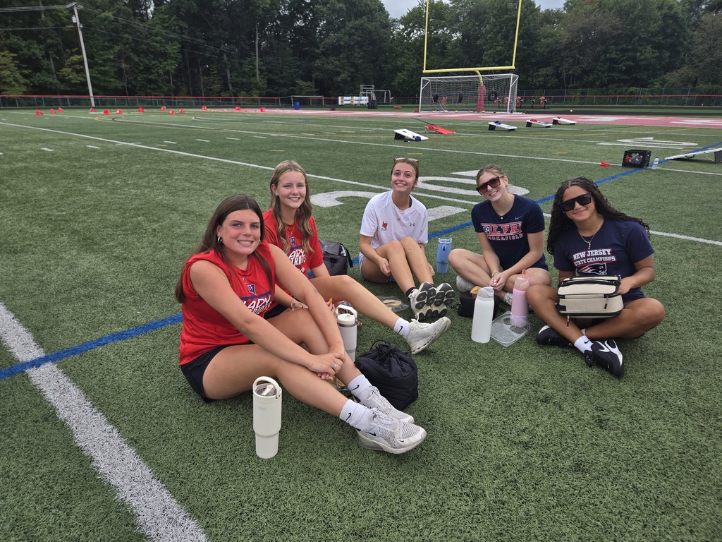 Five Lenape Valley Regional High School students smile for a photo while sitting together on the football field during Future Patriot Day.