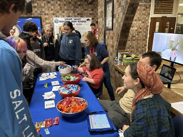 Students gather around the Week of Respect Snacks and Laughs stand, where students and staff share candy and printed cards.