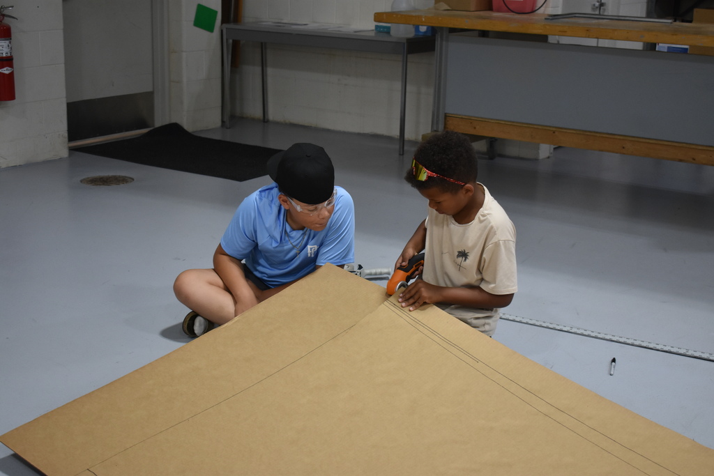 Two students work on building their boat