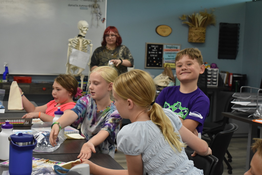 Students working on project while one stops to smile